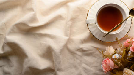 English afternoon tea table setting with beautiful ceramic tea cup, roses bouquet and copy space on minimal white tablecloth. top viewの写真素材
