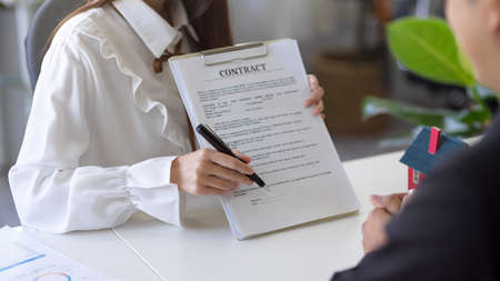 Image in close-up, A female real estate agent hands a rental contract to a new tenant for signing...