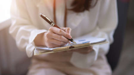 Close-up image, businesswoman or female entrepreneur signing her signature on a documents, approving...