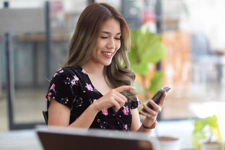 Close-up image, Beautiful asian woman using and holding a modern smartphone in coffee shop. online shopping, social media, online payment.の写真素材