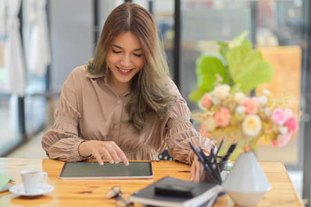 Beautiful woman using digital tablet computer. Businesswoman working on touchpad computer. Female freelance blogger editing her photo on tablet.の写真素材