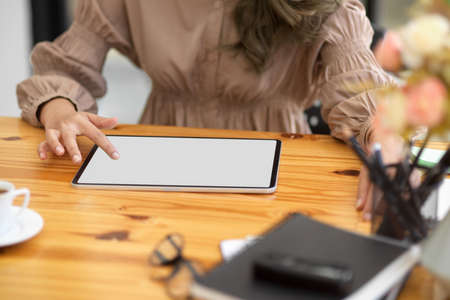 Cropped shot, Female in stylish office dress using digital tablet computer at her office desk. tablet blank screen.の写真素材