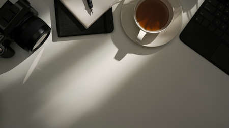 Top view, Flat lay, Modern hipster workspace composition with sunlight shadow, camera, tea cup and...