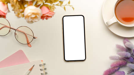 An empty blank smartphone screen mockup with feminine decor on white workspace. top view, flat layの写真素材