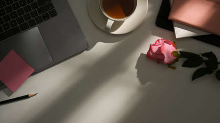 Home office desk workspace with laptop, notebook, coffee cup, copy space, sunlight shadows on white background. Flat lay, top view.の写真素材