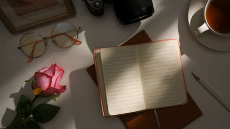 Hipster workspace with sunlight shadow, decor, stationery and empty notebook page mockup. top viewの写真素材