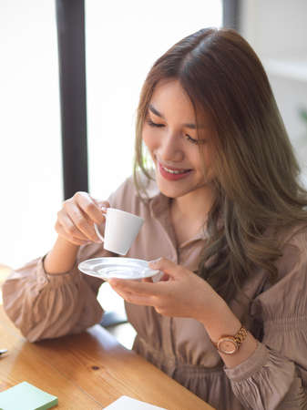 Portrait of a Beautiful charming Asian woman in casual dress sitting in coffee shop and sipping her morning coffee.の写真素材
