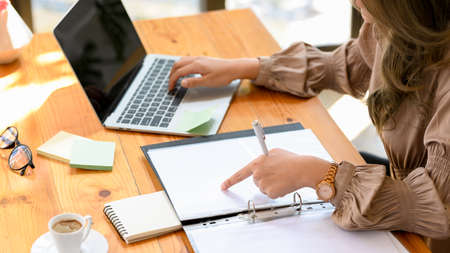 Cropped image, A businesswoman or female accountant working on laptop computer and accounting documents at her office desk.の写真素材
