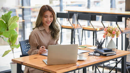 Attractive asian woman officer or businesswoman remote working at cafe co-working space, working on laptop computer.の写真素材