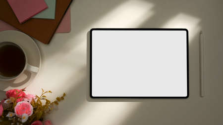Office workplace with supplies, decor and tablet white mockup screen under sunlight shadow. top view