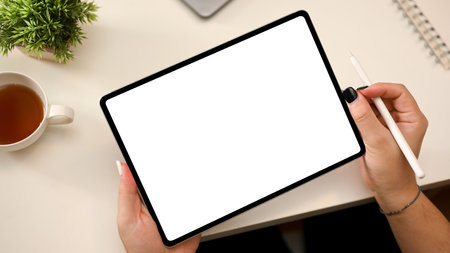 Minimal white office desk with a female holding portable tablet empty screen mockup with stylus pen. designer, drawing, working on tablet touchpad.の写真素材