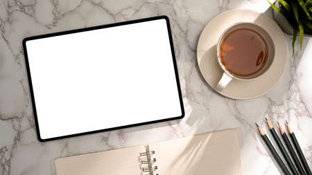 Minimal marble office desk with tablet empty screen mockup, teacup and stationery. top viewの写真素材