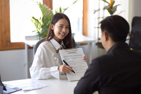 Female insurance broker showing and explaining the contract conditions to male client in the office. insurance agent, real estate agent, realtor.の写真素材