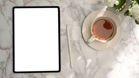Overhead, A digital tablet touchpad white screen mockup, stylus pen and teacup on marble background.の写真素材