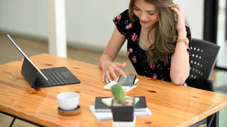 Attractive asian female or college student in casual dress sits in library and relaxes on smartphone application after finished her assignment.の写真素材