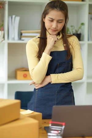 Thoughtful female business start up owner pensive thinking and planning plans for her online marketing campaign.の写真素材