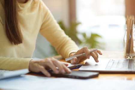 Cropped image of a businesswoman working on laptop computer. Female freelancer typing on laptop keyboard. Female college student doing her online assignment on laptop. focus hands.の写真素材