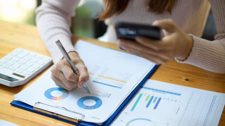 Cropped and focus hands image, A female financial worker working and analysing on financial investment data on report.の写真素材