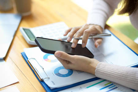 Cropped image and focus hands, Businesswoman using smartphone over her office desk. Female...