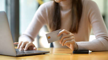 Cropped shot, A charming woman holding a credit card and using laptop computer. Online payment, Money transfer.の写真素材
