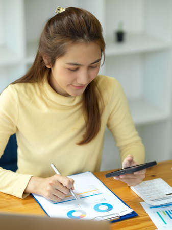 Attractive female financial analysts or financial consultant analysing financial data chart and graph in her office workplace.の写真素材