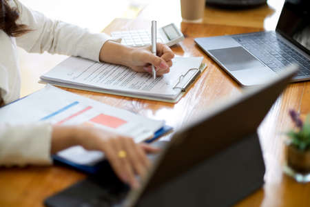 Cropped image of a businesswoman working on portable tablet touchpad computer and filling document form on office table.の写真素材