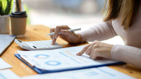Cropped, close-up image, A female accountant or financial assistant using calculator to calculate her business expenses.の写真素材