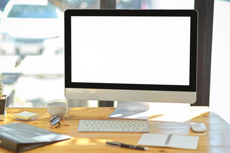 Modern office desk with pc desktop computer white screen monitor, devices, office supplies and stationery on wooden table. Computer desk conceptの写真素材