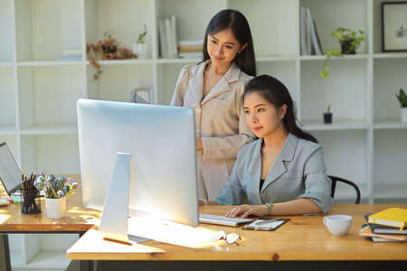 Two professional female marketing manager looking at pc computer screen, checking the details of their campaign together.の写真素材