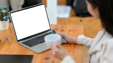 Close-up, A confident businesswoman sipping coffee while working, typing on laptop keyboard. laptop blank screenの写真素材