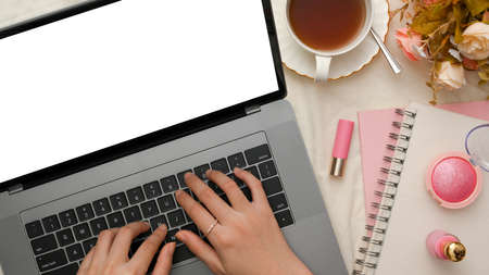 Top view, A female or businesswoman working, typing on laptop keyboard on a modern female office desk. Laptop blank screen.の写真素材