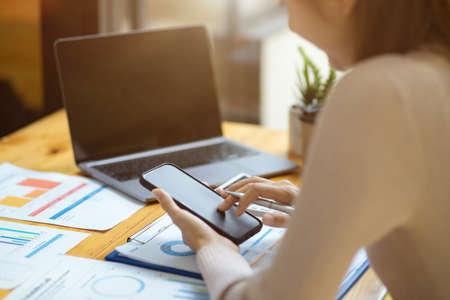 Cropped image, A female accountant using her mobile phone over office desk. Financial investment, Budget planningの写真素材