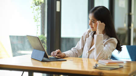 Elegant beautiful Asian businesswoman searching a creative inspiration on the internet, using portable tablet computer.の写真素材