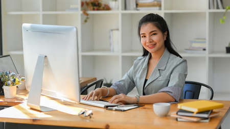 Confident and professional female boss sits at her private office desk and working on pc computer.の写真素材