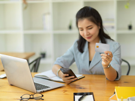 An adult Asian businesswoman paying her bills on mobile application, typing her credit card number on internet banking application.の写真素材