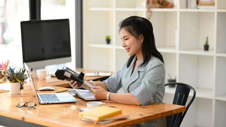 A female receptionist insert a credit card into a payment terminal machine to pay a customer's bill.の写真素材