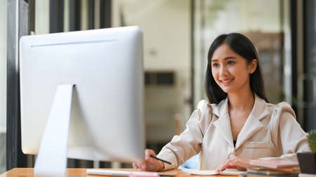 Concentrated asian young businesswoman is working on pc desktop computer in the office workplace.の写真素材