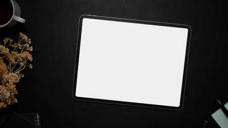 Digital tablet mockup for displaying your graphic on a white screen over a black table background with dried flowers and accessories. top view, flat layの写真素材