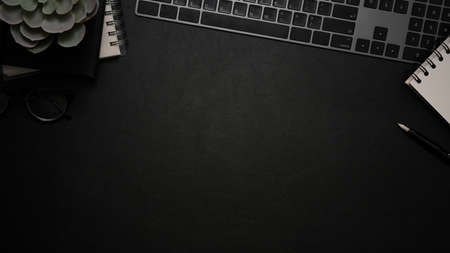 Top view, Modern office table with decor plant, notebook, keyboard and copy space on black background for your text or presentation background.の写真素材
