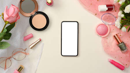 Mockup of a smartphone blank screen on white background surround with female pink beauty cosmetics and decors. top view, flat layの写真素材