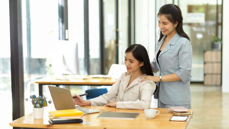 A beautiful supportive female colleague helping her colleague friend to work on the project in the office. teamwork conceptの写真素材