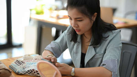 Close-up, Female freelancer sits, in a coffee shop and uses her modern smartphone, text with friendsの写真素材