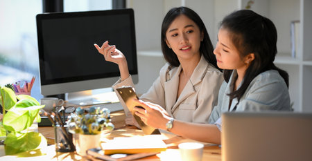 Businesswoman sharing ideas, discussing project with colleague, having pleasant conversation in the office workplace.の写真素材