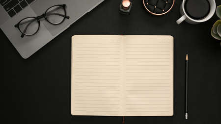 Modern black office desk table with blank notebook pages for input the text in the middle and office supplies. Top view, flat lay.の写真素材