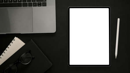 Minimal black office desktop with laptop keyboard, notebook, stylus pen and digital tablet white...
