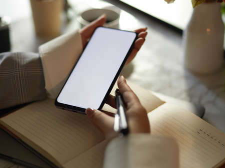 Close-up image, Female hands holding smartphone white screen mockup. Female searching some...