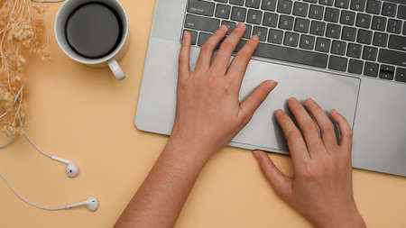 Overhead shot, Focus hands, A female working on laptop computer, typing on notebook keyboard on beige background.の写真素材