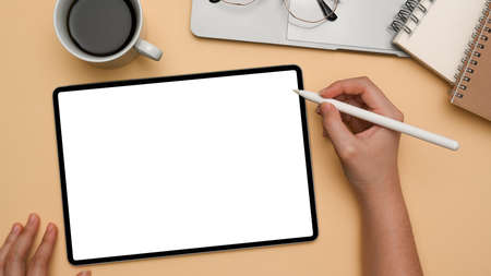 A female designer sketching or drawing graphic image on digital tablet computer over her office...