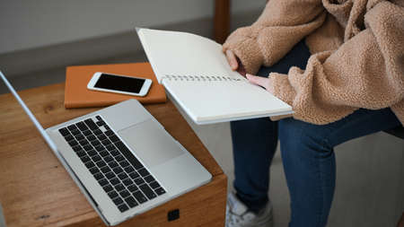 A female freelancer in cozy sweater sits in cafe co-working space and working on her job, reading the assignment.の写真素材