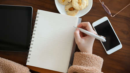 A freelance blogger sketching or drawing some picture on her notebook at cafe. A young female university student writing something on school notebook.の写真素材